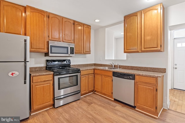 kitchen with appliances with stainless steel finishes, light hardwood / wood-style floors, and sink