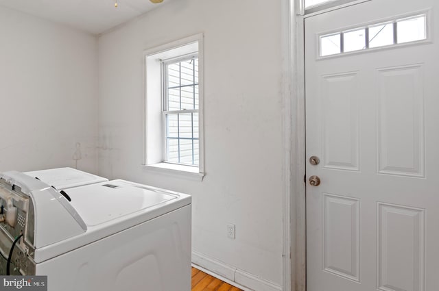 laundry area with washing machine and clothes dryer, a healthy amount of sunlight, and light wood-type flooring