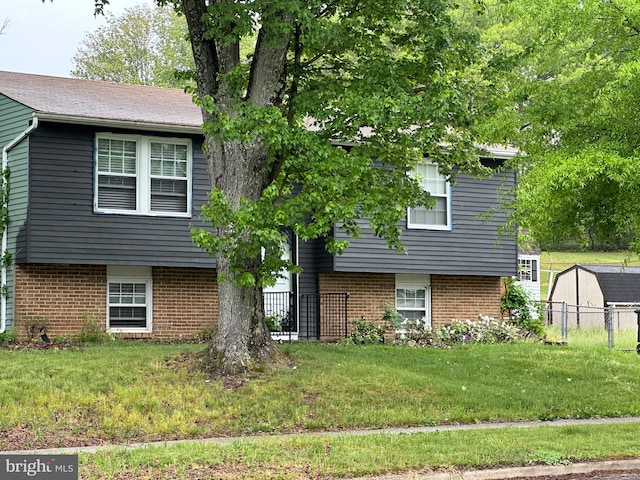 view of front of property with brick siding, fence, and a front lawn