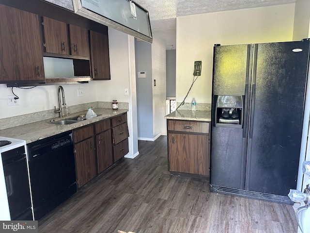 kitchen with a textured ceiling, dark hardwood / wood-style floors, light stone countertops, black appliances, and sink