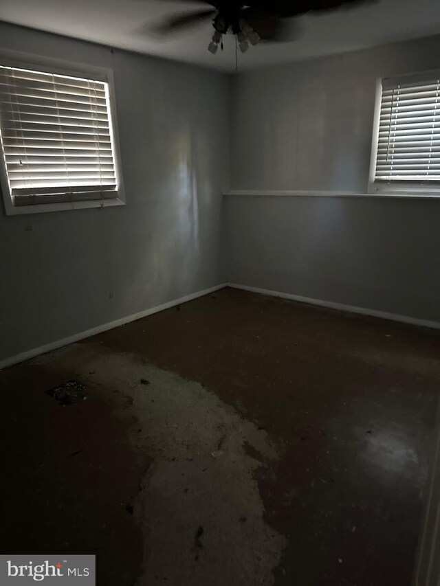 spare room featuring a ceiling fan and baseboards