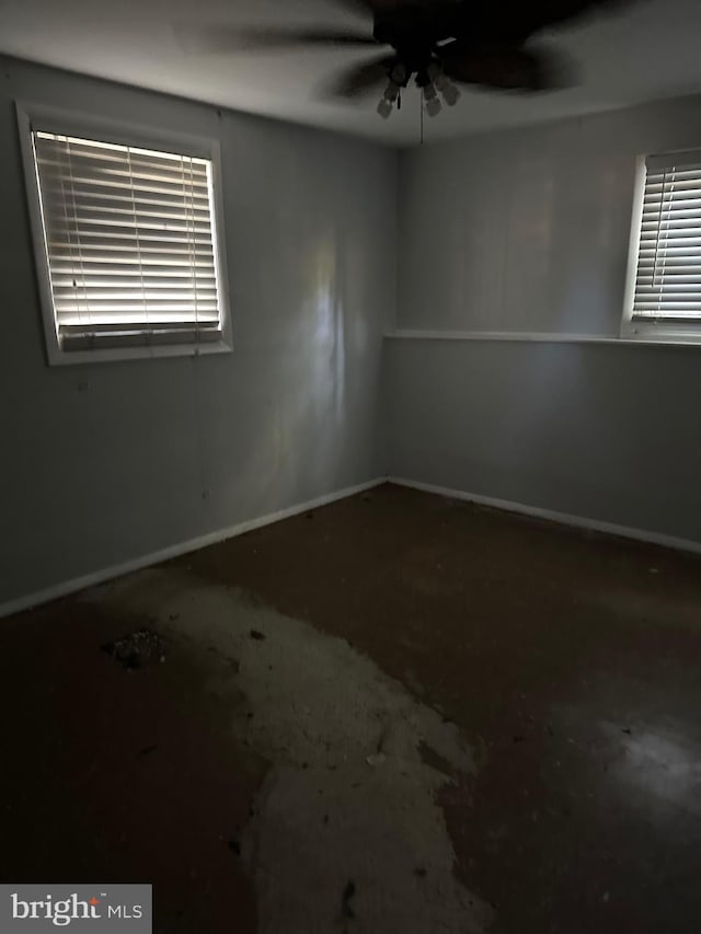 unfurnished room featuring ceiling fan and baseboards