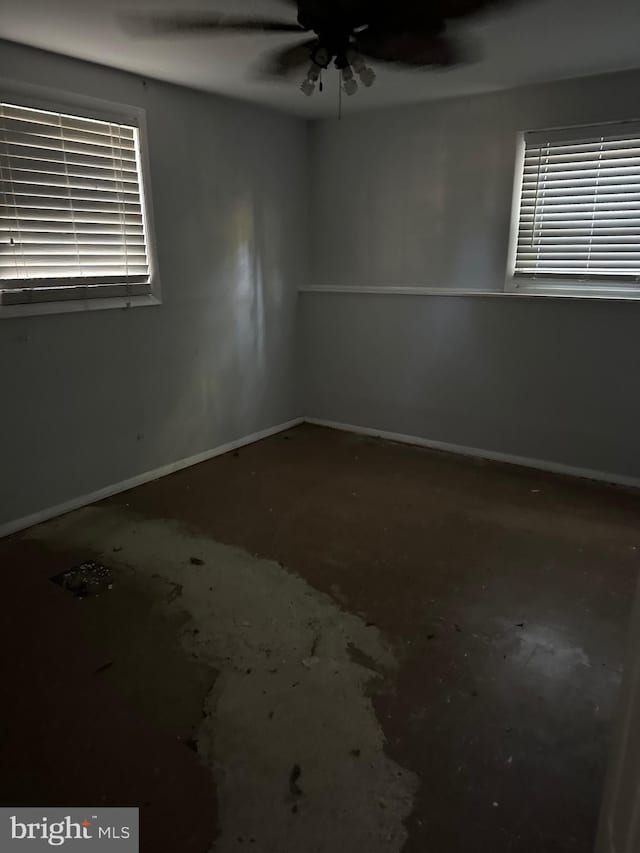 unfurnished room with a ceiling fan and baseboards