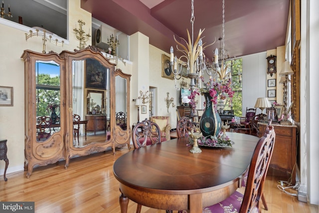 dining area with a notable chandelier, a high ceiling, and light hardwood / wood-style flooring