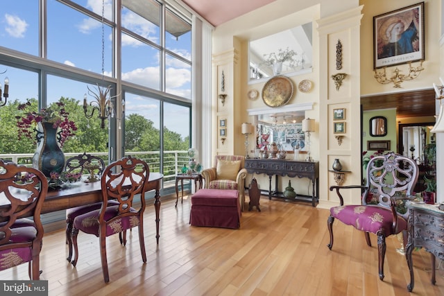 sitting room featuring a high ceiling, a wealth of natural light, a wall of windows, and light hardwood / wood-style flooring