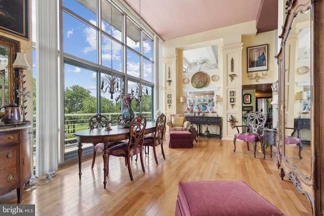 dining space featuring a towering ceiling, plenty of natural light, and light hardwood / wood-style flooring