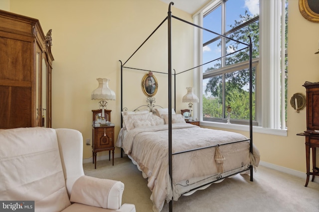 bedroom with a high ceiling, multiple windows, and carpet flooring