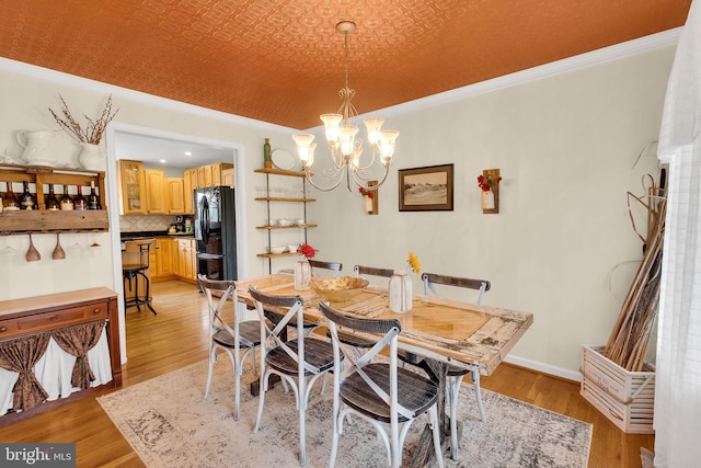 dining space with a chandelier, light hardwood / wood-style flooring, and ornamental molding