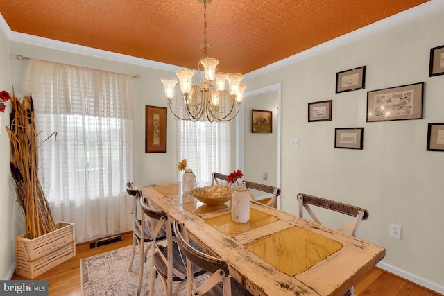 dining area featuring a chandelier, crown molding, light hardwood / wood-style floors, and a textured ceiling