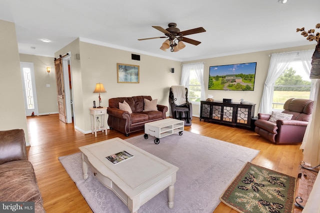 living room featuring ceiling fan, ornamental molding, a healthy amount of sunlight, and light wood-type flooring