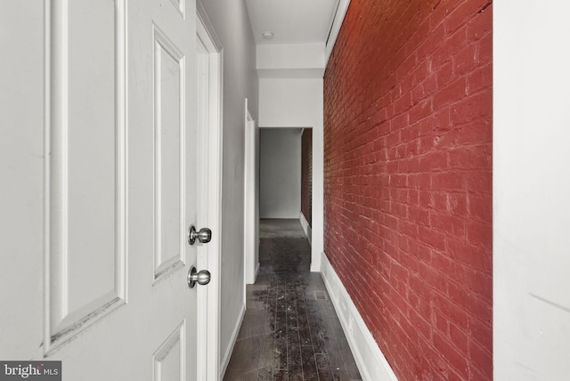 hall featuring dark hardwood / wood-style floors and brick wall