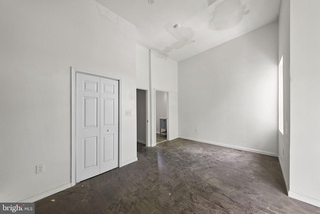 unfurnished room with high vaulted ceiling and dark wood-type flooring