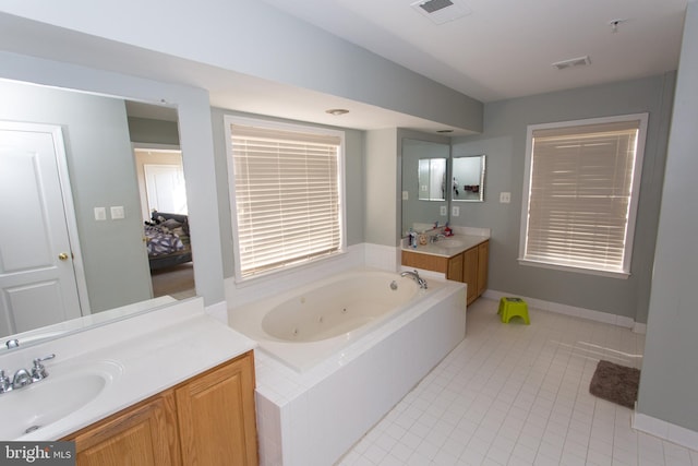 bathroom featuring tiled tub, vanity, and tile patterned floors