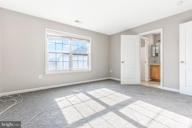 unfurnished bedroom featuring ensuite bathroom and carpet