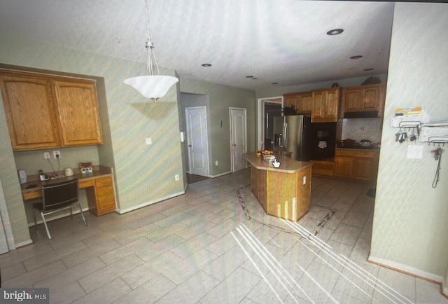 kitchen with built in desk, a center island, pendant lighting, and stainless steel fridge with ice dispenser