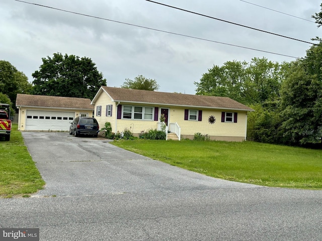 view of front of home with a garage, a front yard, and an outdoor structure