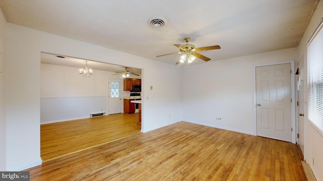 empty room featuring ceiling fan with notable chandelier and light hardwood / wood-style floors