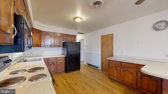 kitchen with light hardwood / wood-style floors, black appliances, and sink