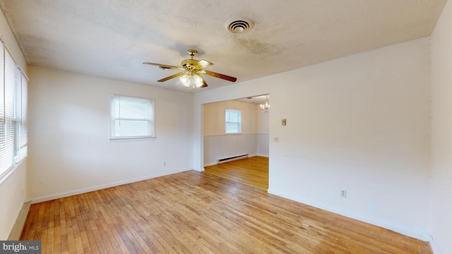 empty room featuring ceiling fan, a textured ceiling, baseboard heating, and light hardwood / wood-style floors