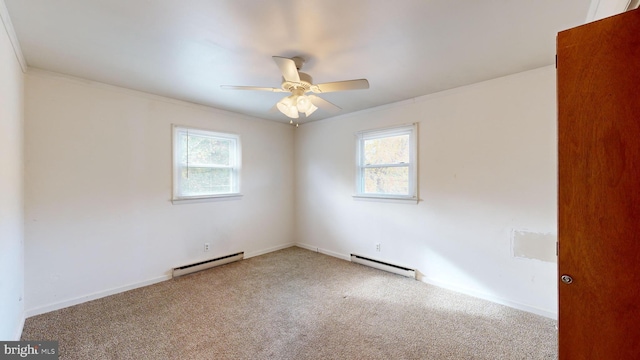 carpeted spare room with a baseboard heating unit, a wealth of natural light, and ceiling fan