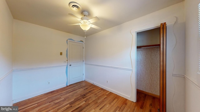 unfurnished bedroom featuring a closet, wood-type flooring, and ceiling fan