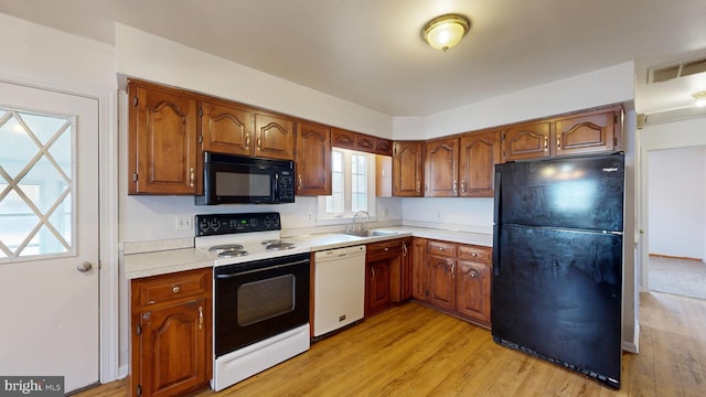 kitchen with sink, black appliances, and light hardwood / wood-style flooring