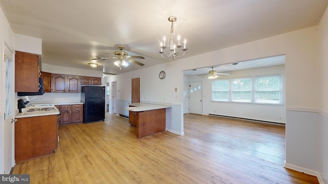 kitchen with a baseboard radiator, black fridge, light hardwood / wood-style floors, and decorative light fixtures