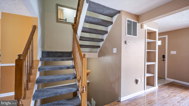 stairs featuring hardwood / wood-style floors and a textured ceiling