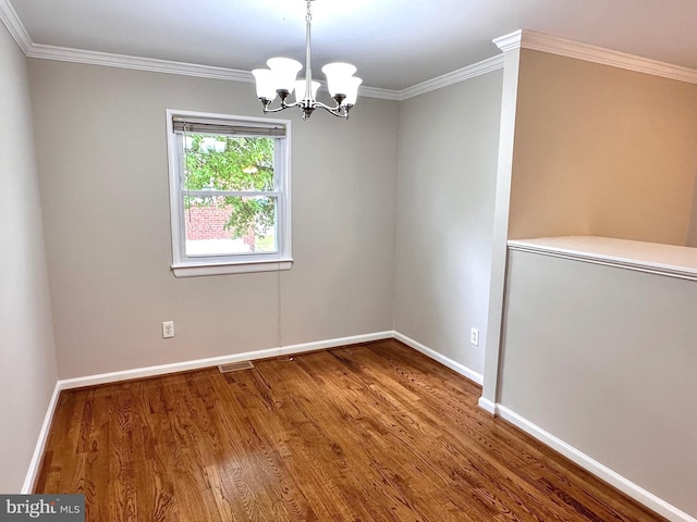 spare room featuring an inviting chandelier, hardwood / wood-style floors, and crown molding