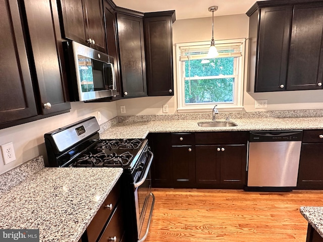 kitchen featuring sink, light hardwood / wood-style flooring, appliances with stainless steel finishes, decorative light fixtures, and dark brown cabinetry