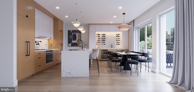 kitchen with stainless steel oven, sink, hanging light fixtures, and wine cooler