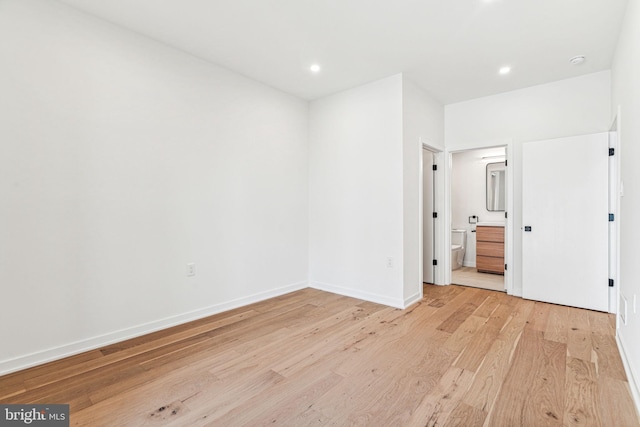 unfurnished bedroom featuring ensuite bathroom and light hardwood / wood-style flooring