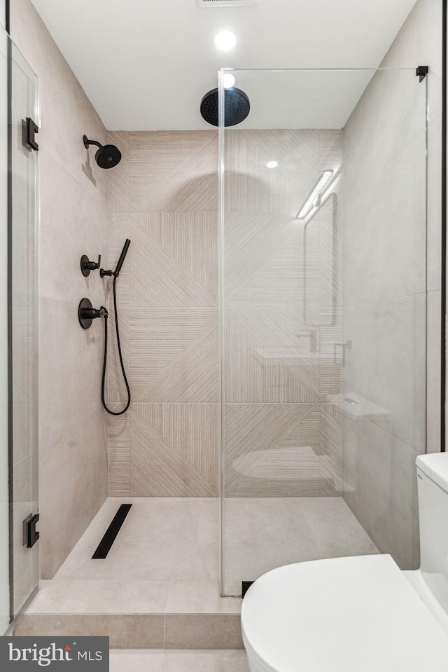 bathroom featuring toilet and a shower with shower door