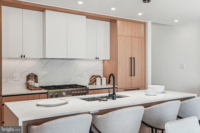 kitchen with light stone countertops, sink, and white cabinets