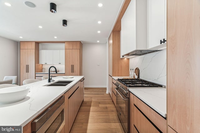 kitchen featuring backsplash, sink, appliances with stainless steel finishes, light hardwood / wood-style floors, and white cabinetry