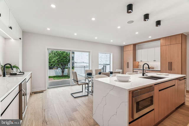 kitchen with white cabinets, a large island, stainless steel microwave, and sink