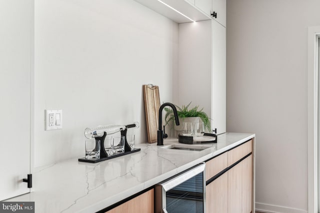 bar featuring light stone countertops, wine cooler, and sink