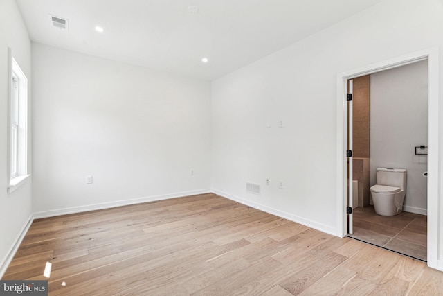 unfurnished bedroom featuring connected bathroom and light hardwood / wood-style flooring