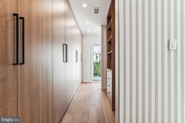 hallway featuring built in shelves and light hardwood / wood-style flooring