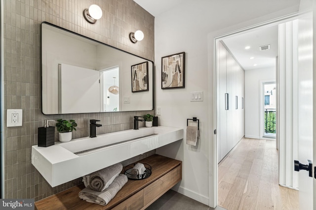 bathroom featuring vanity, hardwood / wood-style floors, and backsplash