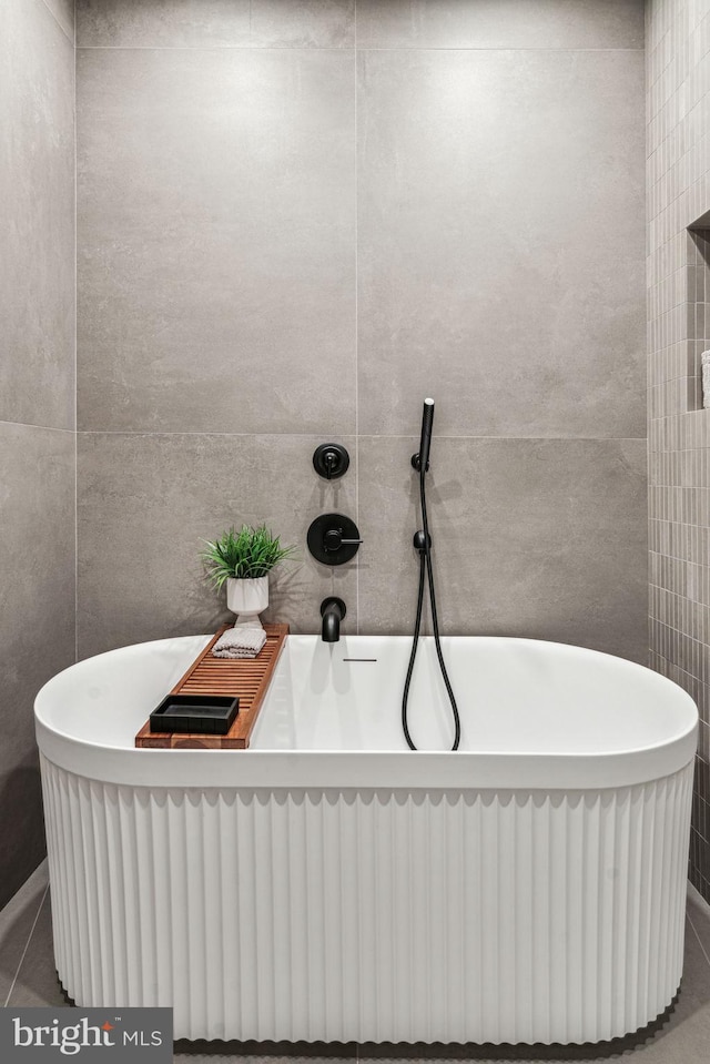 bathroom featuring tile patterned floors, a tub, and tile walls