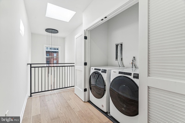 washroom featuring washer and dryer, light wood-type flooring, and a skylight