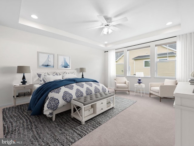 carpeted bedroom featuring a raised ceiling and ceiling fan