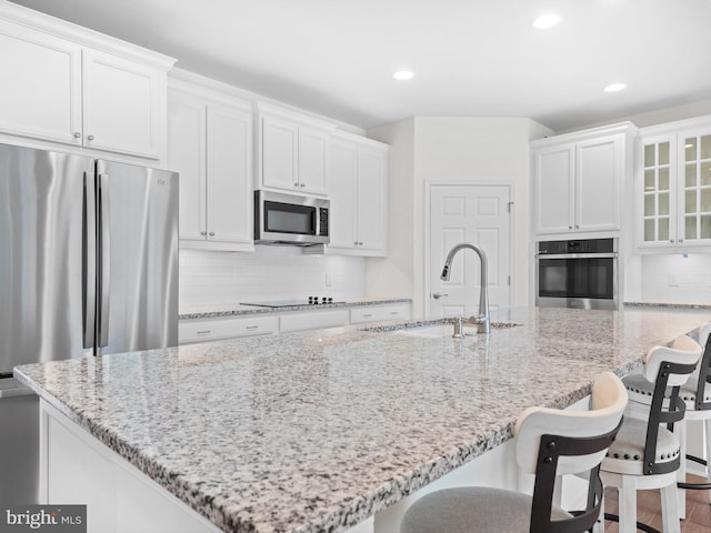 kitchen with stainless steel appliances, sink, an island with sink, and backsplash