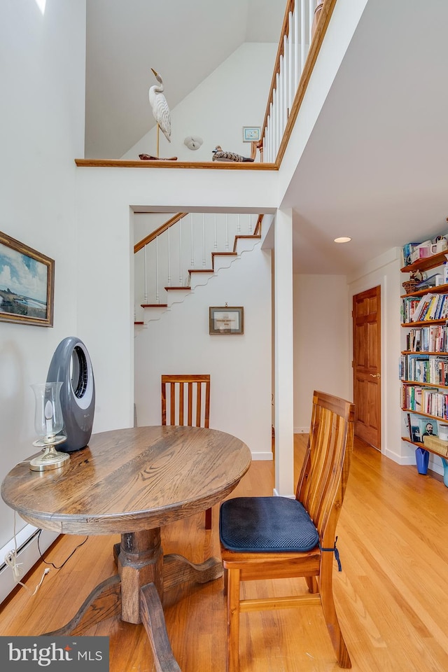 dining area with light wood-type flooring and high vaulted ceiling