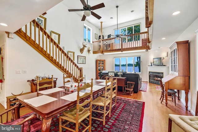 dining area with a high ceiling, light hardwood / wood-style floors, ceiling fan, and plenty of natural light