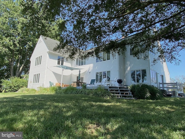 rear view of property featuring a lawn and central air condition unit