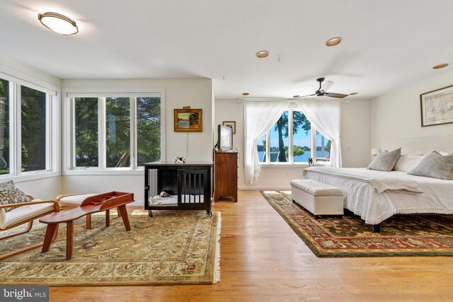 carpeted bedroom with a water view, vaulted ceiling, multiple windows, and baseboard heating