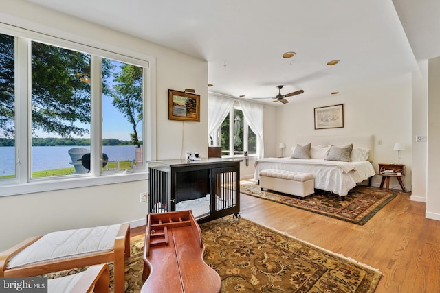 bedroom featuring a water view, baseboards, and wood finished floors