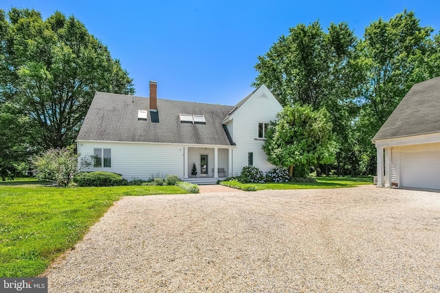 rear view of house featuring a yard, driveway, a chimney, and a garage